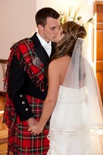 groom in scottish dress kisses bride