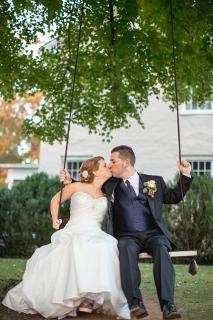 bride and groom kiss on swing