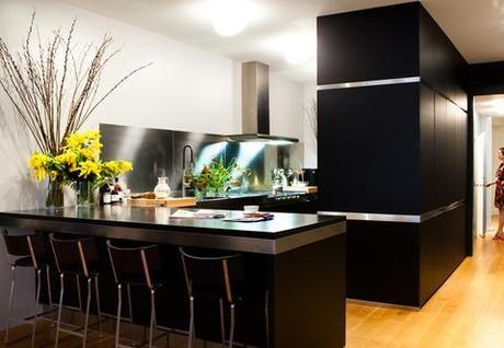 modern kitchen with stainless steel finishes, black cabinetry, and granite countertops