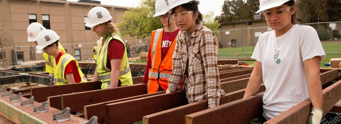 Stanford students, from right, Erica Levine, Yoo-Yoo Yeh, Claire Frykman, and classmates prepare to place floor joists that will support a deck at the Start.Home. (Photo: Linda A. Cicero / Stanford News Service)