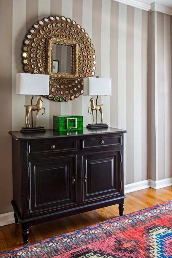 Design Manifest Hallway black chest, peacock mirror, Turkish rug, striped wall