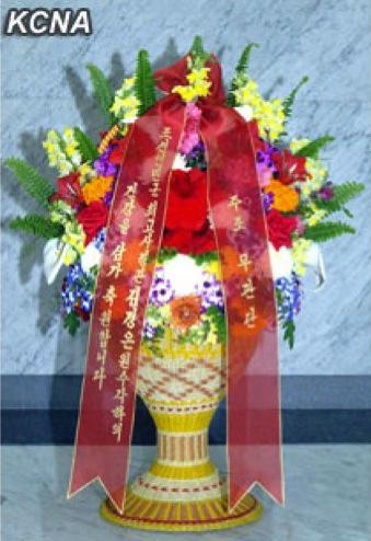 A floral basket delivered by foreign military attaches stationed in the DPRK, sent to Kim Jong Un, to commemorate the 20th anniversary of his father, Kim Jong Il's election as chairman of the National Defense Commission.  The floral basket was delivered by Iranian military attache Hassan Reza Husseini, dean of foreign military attaches in the DPRK, and accepted by Gen. Kim Kyok Sik, Minister of the People's Armed Forces, on 8 April 2013.  (Photo: KCNA)