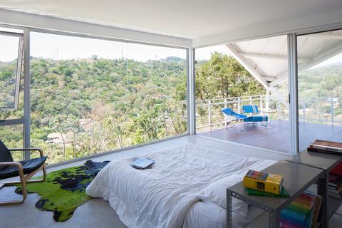 master bedroom with floor-to-ceiling glass walls in a modern house in el salvador with creative roofing