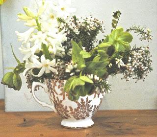 White hyacinths, white heather and green hellebores in a gold and white china teacup.