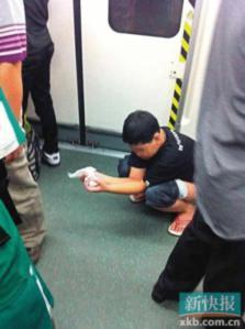 A Chinese man taking a crap right on the floor of a Chinese train, surrounded by other people.