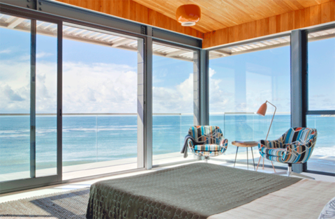 Oceanside bedroom with floor-to-ceiling glass windows