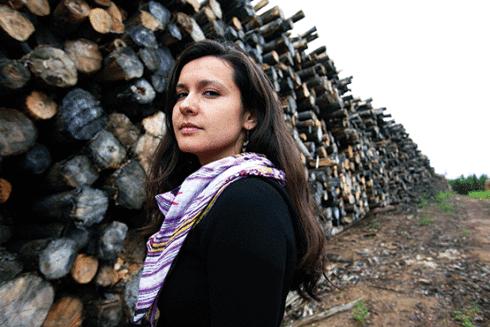 Melina Laboucan-Massimo stands next to logs from clearcuts at a proposed tar sands site north of Fort McMurray, northern Alberta, Canada. Photo by Jiri Rezac.