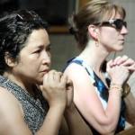 Myrna Abad (left) and Christina Mahan from St. Ignatius Parish, Yardley, pray during benediction at St. John the Evangelist, Morrisville, after processing from their parish.