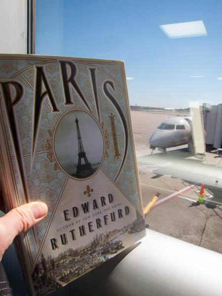 Holding the book Paris by Edward Rutherfurd in front of the plane at Lambert Airport