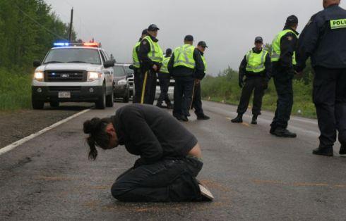 Susanne Patles in prayer, as New Brunswick RCMP confer. (Photo: M. Howe)