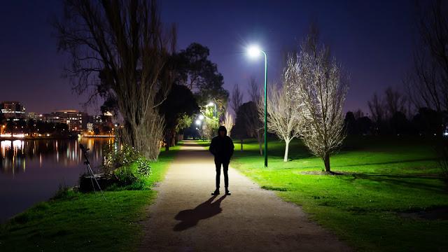 man standing beside albert park lake at night