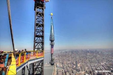 Ironworkers at #One WTC look on as the final flag-draped section of spire is hoisted to the top of the building.