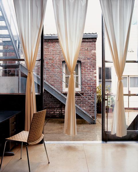 curtains to deck with brick building adjacent 