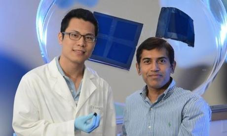 Zenan Yu and Jayan Thomas hold samples (magnified in the background) of nanopillar structures they printed. (Credit: UCF)