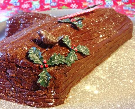 icing and edible glitter snow on christmas chocolate yule log holly leaves and robin cake decoration