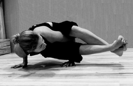 Woman in astavakrasana, a bound hand balancing pose.