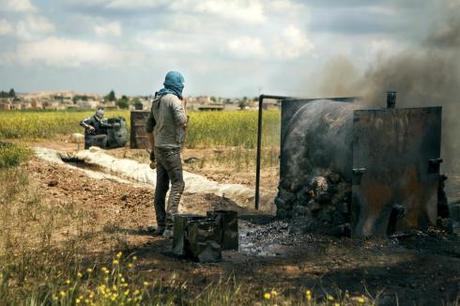 Abu Zechariah's sons work with their father, with one standing by the refinery and the other collecting the produced diesel in an oil barrel.