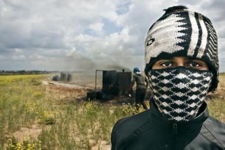 One of Abu Zechariah's sons covers his mouth and nose while working with the refinery to avoid inhaling smoke emitted from the rusty tank.