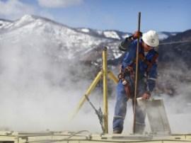 A worker checks a dipstick to check water levels and temperatures in a series of tanks at a fracking operation at a gas drilling site outside Rifle, Colorado. (AP/Brennan Linsley) 