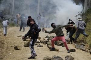 Stone throwers clash with riot police as Colombian farmers demanding government subsidies and greater access to land block the road in La Calera, Cundinamarca department, on August 23, 2013. A five-day-old farmworkers' protest in Colombia claimed its first fatality Friday when a man on a motorcycle crashed and died at a roadblock, police said Friday. Since the protests began Monday, farmworkers have closed roads at dozens of points in across the country, blocking the passage of cargo trucks and other vehicles from makeshift camps erected on sides of roads.  (EITAN ABRAMOVICH/AFP/Getty Images)