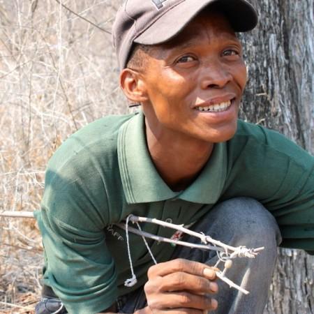 Elvis demonstrating how to attach the nut to the stick to catch a guinea fowl in Namibia.