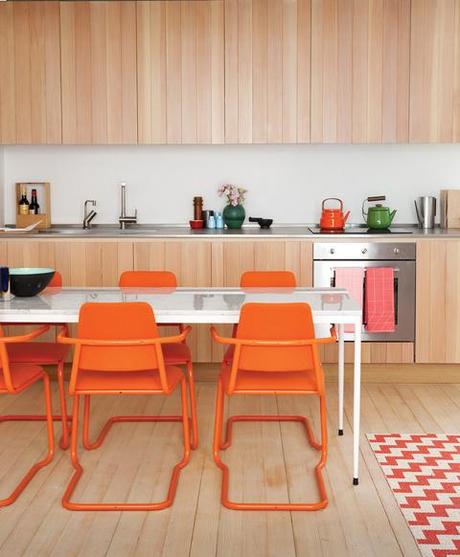 Modern custom-built kitchen with bright orange chairs 