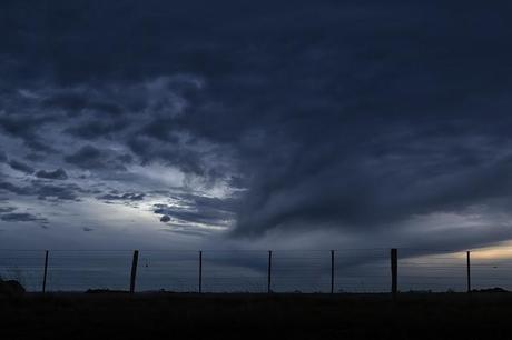 dark cloud over barbed wire fence