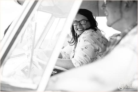 Engaged couple sit behind the wheel of VW camper van 