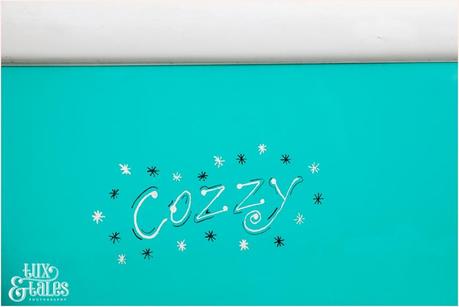 Script text that says Cozzy on a teal vintage camper van 