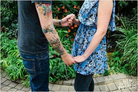 Engagement shoot pose of couple holding hands with tattooed groom 