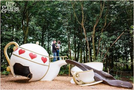 Couple pose on top of alice in wonderland style teapot at Stockeld Park 