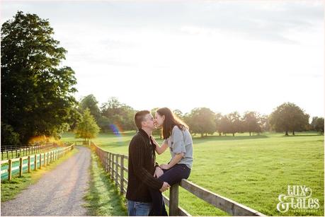 couple kissing whilst sitting on a fence at Stockeld Park 