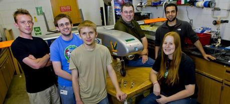 A team of Clarkson engineering students and staff pose with the Golden Eagle, an unmanned aerial vehicle constructed last year. The parts in the foreground will go on the new UAV the team is designing. In the front row, from left to right: Jacob T. Miller, Sean Shea, Ryan Feldman, and Cassandra Christman. In the back, Dan Valyou, left, a senior specialist in Clarkson’s Civil and Environmental Engineering Department, and Omer Bakshi. (Credit: Clarkson University)