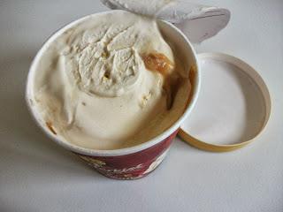 A tub of popcorn flavoured ice cream with toffee sauce, popcorn and crunchy toffee pieces