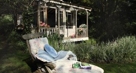 ilovegreeninspiration_Small-Island-Cottage-With-A-Traditional-Interior-with-white-wooden-wall-terrace-design-glass-door-window-flower-decor-and-chair-with-blue-pillow-and-forest-view-554x300