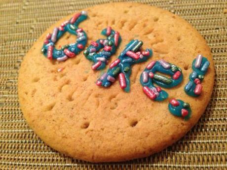 bake writing on cookie adorned with sugar sprinkles using silver spoon blue writing icing