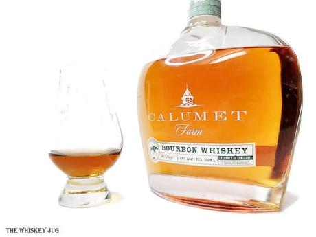 White background tasting shot with the Calumet Farm Bourbon bottle and a glass of whiskey next to it.