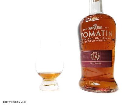 White background tasting shot with the Tomatin 14 Years Port Casks bottle and a glass of whiskey next to it.