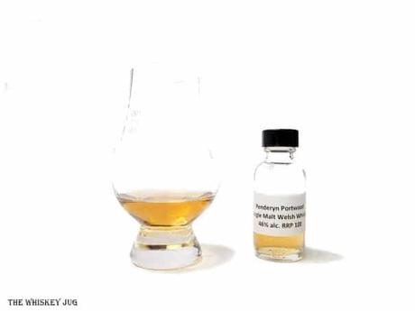 White background tasting shot with the Penderyn Portwoood Single Malt sample bottle and a glass of whiskey next to it.