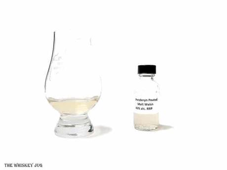 White background tasting shot with the Penderyn Peated Single Malt sample bottle and a glass of whiskey next to it.