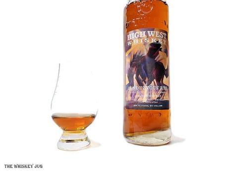 White background tasting shot with the High West Rendezvous Rye 21C23 bottle and a glass of whiskey next to it.