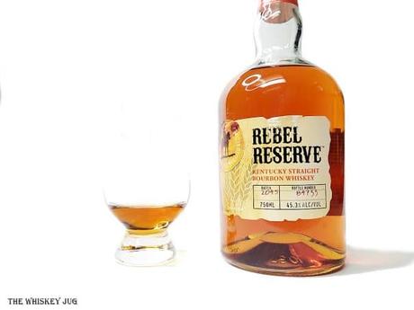 White background tasting shot with the Rebel Yell Rebel Reserve bottle and a glass of whiskey next to it.