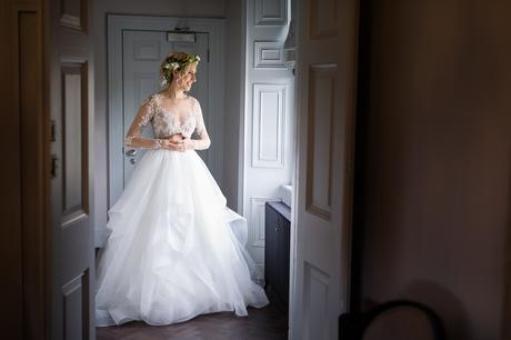 Bride in flower crown looks out window