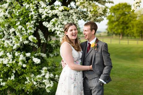 Bride in flowered wedding dress laughing with groom at Barmbyfield Barns