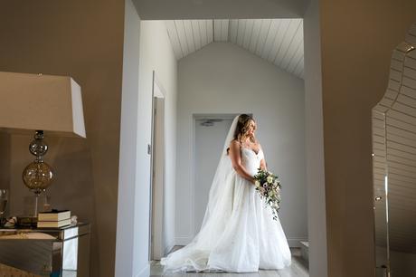 Bride standing in doorway showing off lace dress