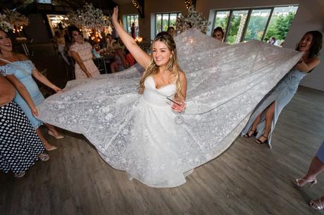 Bride's gruses lift the lace on her dress during the party