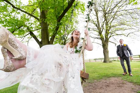 Groom [ushes bride in flwoered dress on swing