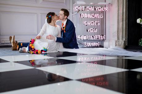 Bride and groom kiss in front of neon sign at Yorkshire wedding