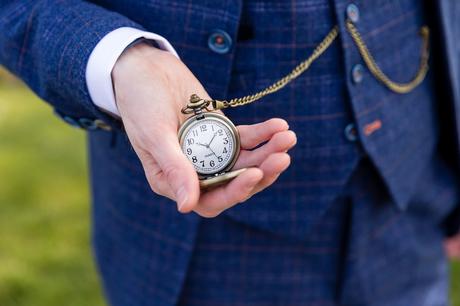 Groom in blue checqued suit holds a pocketwatch at Yorkshire wedding