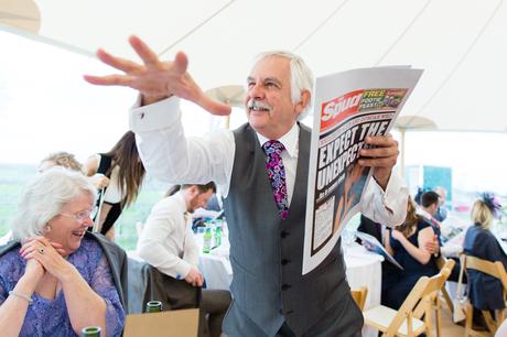 Wedding guest holding a newspaper drescribing something with big hand gestures